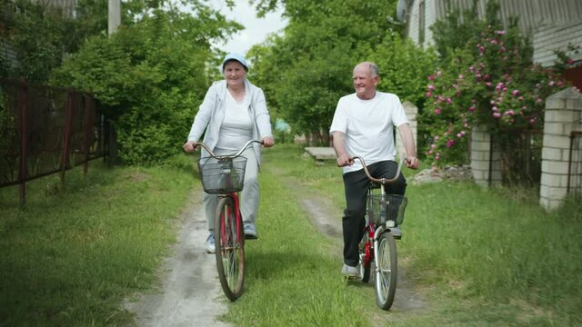 outdoor activities, happy elderly man and woman enjoying cycling, an old joyful couple have fun while cycling on weekend in countryside