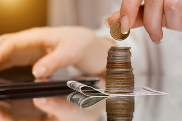 girl puts a copper coin in a stack of money counted on the tablet