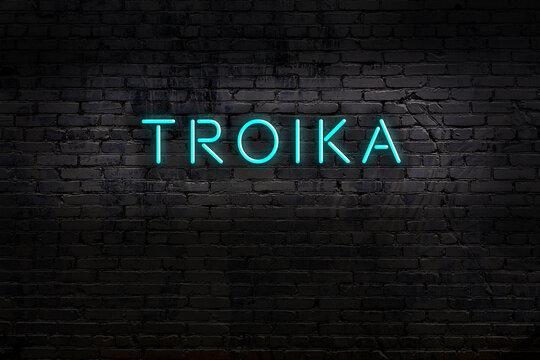 Neon sign. Word troika against brick wall. Night view
