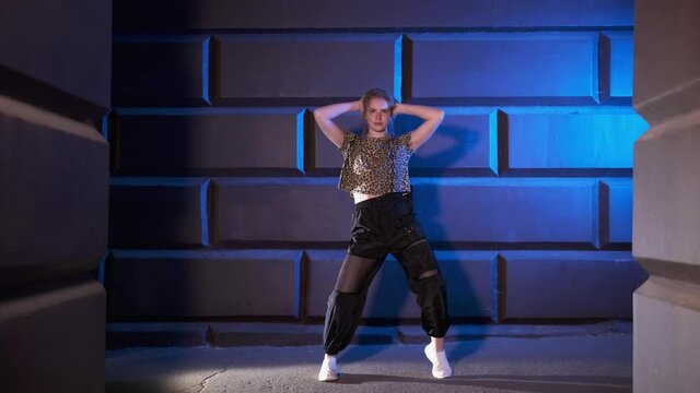 young girl dancer dancing modern street dance against the wall in the late evening. Contemporary choreography. Youth subculture