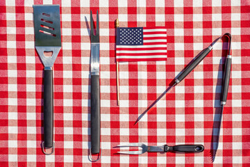 Metal grill tools layed out on a picnic table ready for a weekend barbecue