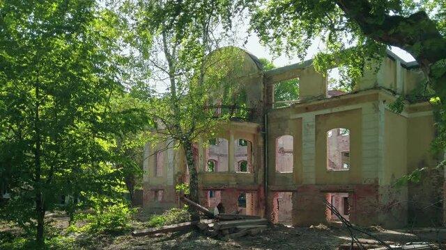 Old german mansion - abandoned and ruined historical building among green trees in Kaliningrad, Russia (formerly Koenigsberg) at sunny spring day. Static shot rendered in 4K