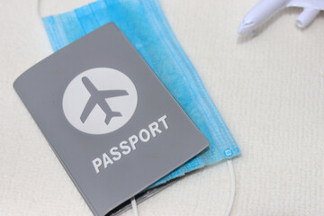 Passport with medical face mask and blurred airplane on white background. Lifestyle and travel concept in New Normal after Covid-19 / Coronavirus.