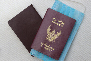 Thai Passport with medical face mask on white background with copy space. Lifestyle and traveling concept in New Normal after Covid-19 / Coronavirus pandemic.