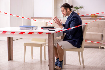 Young male employee working at home during pandemic disease