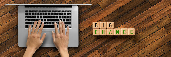 hand is typing on a computer and cubes with message BIG CHANCE on wooden background