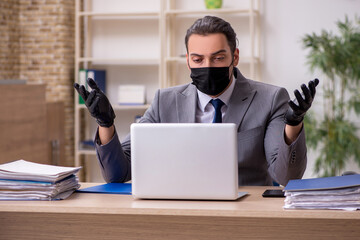 Young male employee in the office during pandemic disease