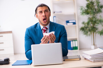 Sick male employee suffering at workplace from coronavirus