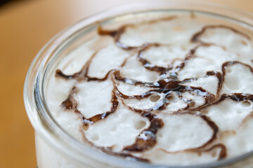 Mocha Coffee and Chocolate Art on Frothing Milk at Right Frame on Wood Table