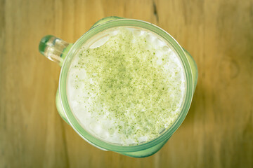 Cold Matcha Green Tea Beverage and Frothing Milk and Top View Green Tea Powder Topping in Vintage Tone