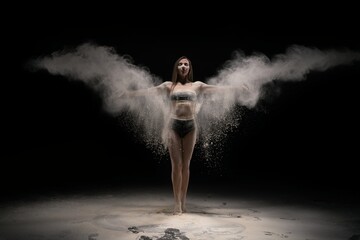 Fototapeta na wymiar Brunette woman in sportswear throwing sand in air