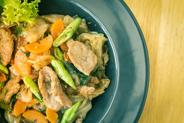 Stir Fried Noodle and Pork and Carrot and Yardlong Beans and Lettuce with Black Soy Sauce on Top View with Natural Light on Left Frame in Vintage Tone