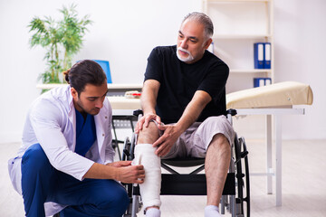 Fototapeta premium Old injured man visiting young male doctor traumatologist