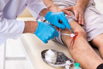 Leg injured man visiting old doctor in first aid concept