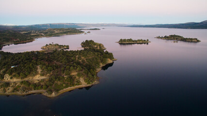 The lake at sunset. Aerial view of the islets, lake, coastline and forest at nightfall.