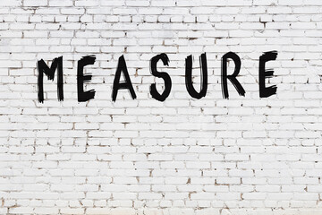 Inscription measure painted on white brick wall