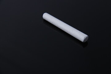 Chalk with black background isolation. Concept of a school tool photo or learning with shadow reflection underneath