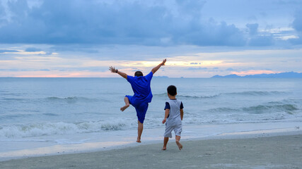 Blue sky and two children enjoy and action jumping on the beach.