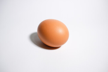 A single chicken egg that layed down on a white background