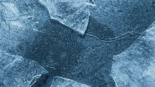 Close-up of melting ice texture. Studio shot close-up of the blue surface of cracked melting ice in time lapse.