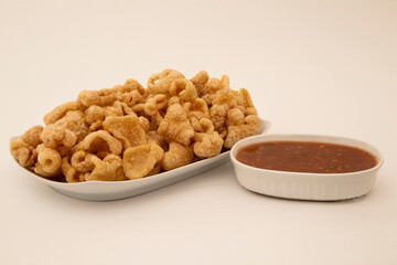 pork rind in bowl and on white background and red spicy sauce