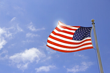 Obraz premium USA - American flag close up with the sunlight and blue sky in the background.