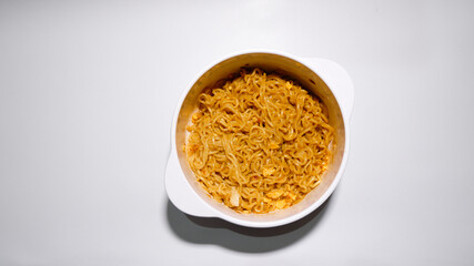 A tasty instant fried noodle (Indomie Goreng) mixed with scrambled boiled egg in a white bowl. Top view of delicious fried noodle