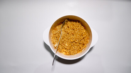 A tasty instant fried noodle (Indomie Goreng) mixed with scrambled boiled egg in a white bowl. Top view of delicious fried noodle