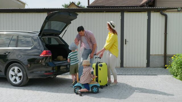summer vacation, happy loving family with children going on trip by car load traveling suitcase in trunk for trip to summer resort