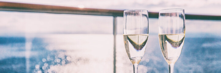 Two champagne glasses or sparkling white wine flutes on ocean landscape background, panorama banner...
