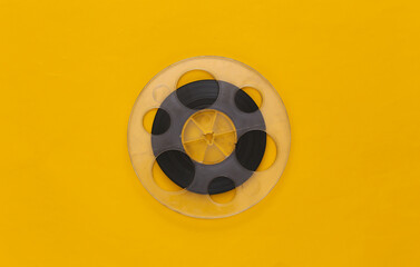 Audio magnetic tape. Film reel on yellow background. Top view. Retro style. 80s