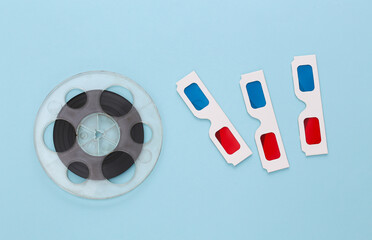 Film reel and anaglyph 3D glasses on  blue background. Entertainment industry. Cinema. Top view