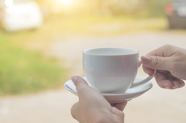 white coffee cup on hand in green park background