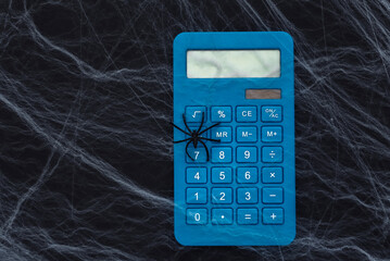 Calculator on a black background with cobwebs and spiders. Halloween theme. Arachnophobia