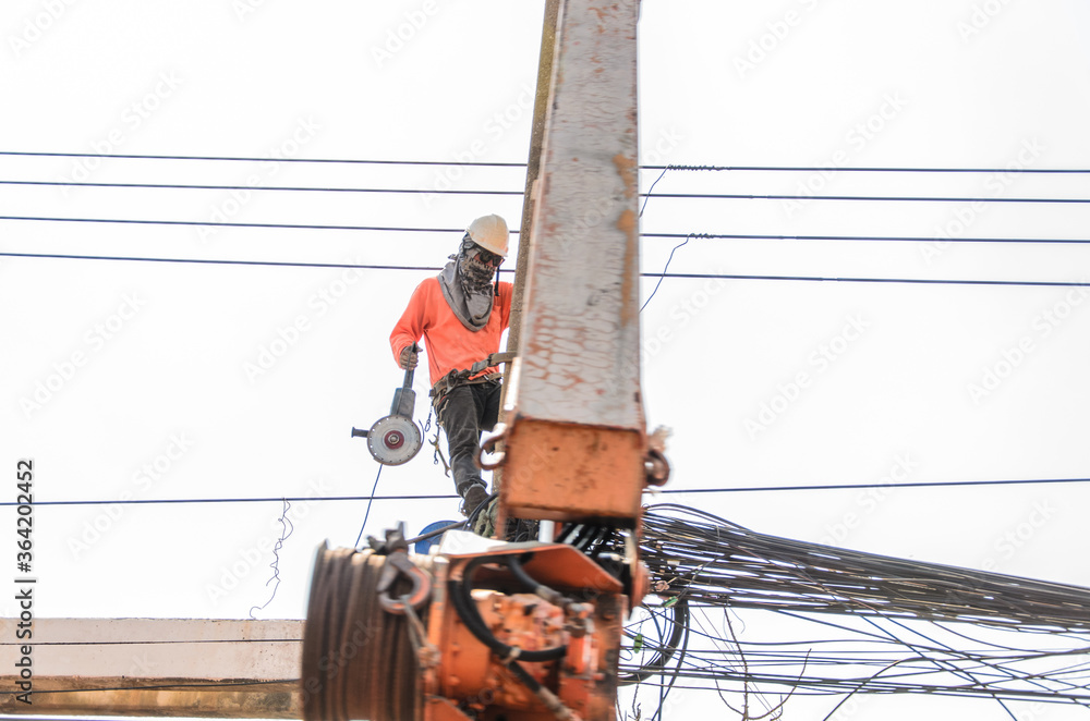 Wall mural echnician is repairing the power transmission line on the power post.