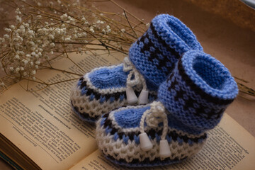 Handmade crocheted booties on an old vintage book with dried flowers