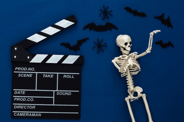 Horror movie, halloween theme. Movie clapperboard, skeleton, spiders and flying decorative bats on...