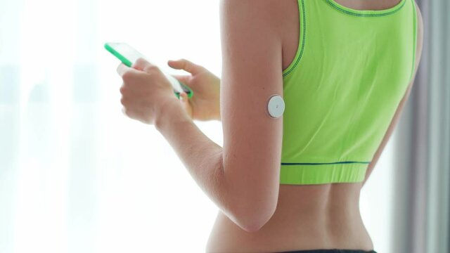 Woman diabetics control and checking glucose level with a remote sensor and smartphone. Online monitoring glucose levels without blood. Digital medical technology in diabetes treatment, health care