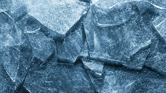 Close-up of melting ice texture. Studio shot close-up of the blue surface of cracked melting ice in time lapse.