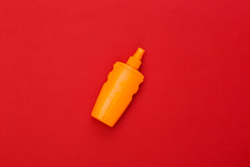 Sunblock bottle on red bright background. Skin protection. Beach vacation. Top view
