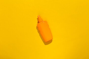 Sunblock bottle on a yellow bright sunny background. Skin protection. Beach vacation. Top view