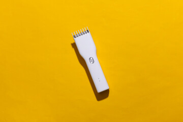 Wireless hair clipper on yellow bright background. Top view
