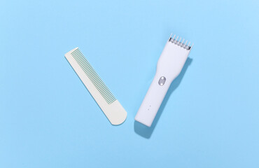 Wireless hair clipper and comb on blue bright background. Top view