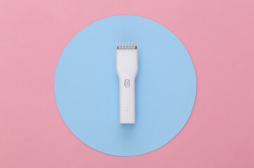 Wireless hair clipper on pink background with blue circle. Top view