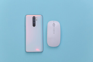 Modern smartphone back with lenses and white pc mouse on a blue background. Top view