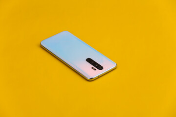 Modern smartphone back with lenses on yellow background
