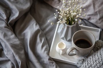 Cozy breakfast in bed, cup of coffee and milk on the grey fabric, space for text. Breakfast in bed.