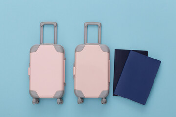 Travel planning. Two toy travel luggage and passport on blue pastel background. Top view. Flat lay