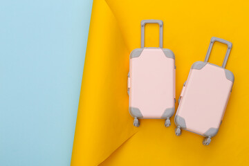 Travel planning. Two toy travel luggage on yellow blue background. Top view. Flat lay. Copy space