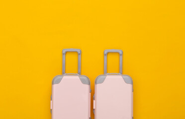 Travel planning. Two toy travel luggage on yellow background. Top view. Flat lay